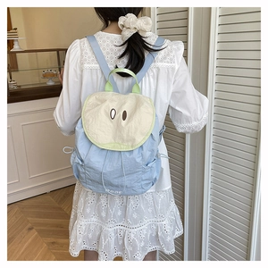 Detail of light blue nylon pear backpack with cartoon eyes flap and side drawstring