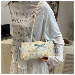 Detail of floral jacquard tote bag featuring a blue bow and silver heart pendant