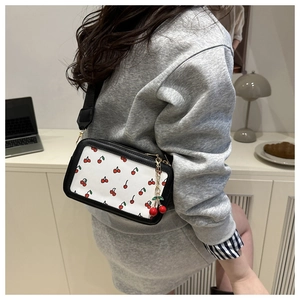 Close-up of a rectangular crossbody bag featuring cherry patterns and a cute cherry charm