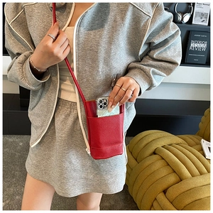 Macro detail of red lychee textured leather mini crossbody phone bag with slim shoulder strap