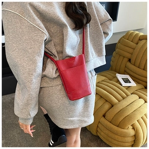 Detail view of red lychee textured leather crossbody phone bag on a stylish model