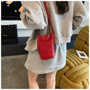 Detail of red lychee grain leather mini bucket bag with front pocket on model