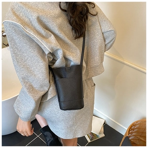 Detail of minimalist black pebbled leather mini crossbody phone bag on model
