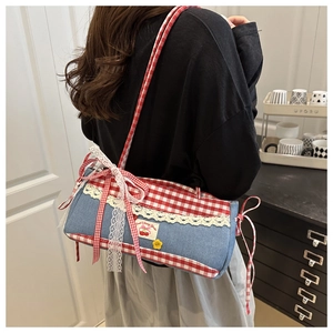 Détail du sac à carreaux rouges avec dentelle blanche, broderie cerise et bouton jaune