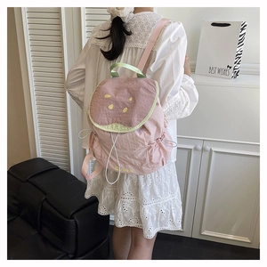 Detail of cute pink guava backpack with green straps and soft nylon fabric texture