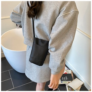 Detailed view of black litchi pattern bucket bag styled as a crossbody commute purse