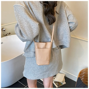 Close-up of beige lychee texture leather mini bucket bag with slim shoulder strap