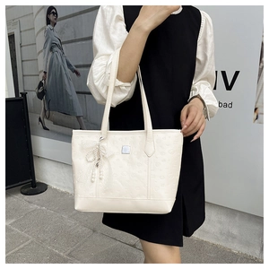 Détail du sac cabas blanc avec texture cœur gaufrée et breloque nœud en perles