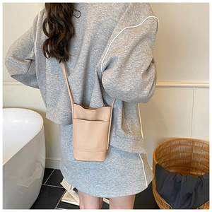 Detail of compact beige cross-body phone bag featuring lychee texture and slim strap