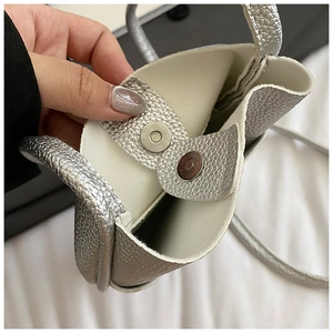 Detail of silver lychee texture leather bag with a round metal magnetic snap closure