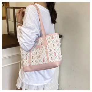 Detail of cute pink and white tote bag showing cartoon patterns and leather handles
