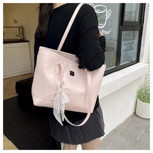 Détail du sac cabas rose avec motifs en relief, nœud en dentelle et breloque perle