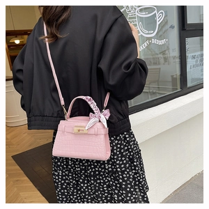 Pink faux leather bag with crocodile texture and silk scarf handle detail in street setting