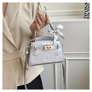 Detail of silver crocodile-embossed handbag with gold twist lock and printed scarf