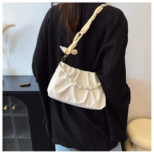 Detail of white pleated cloud bag with pearl chain and yellow silk scarf shoulder strap