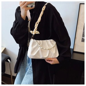 Close-up of white ruched cloud bag featuring pearl chain and silk scarf strap details