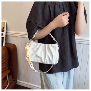 Close-up of white ruched cloud bag with pearl handle and yellow silk scarf strap