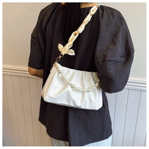 Detail of white pleated cloud bag featuring large pearl chain and silk scarf handle