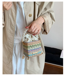 Detail of colorful woven straw bag with pearl handle and metal chain strap details