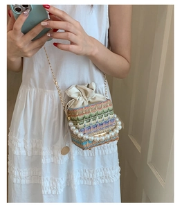 Detailed shot of a colorful woven bucket bag with pearl handle and leather drawstring