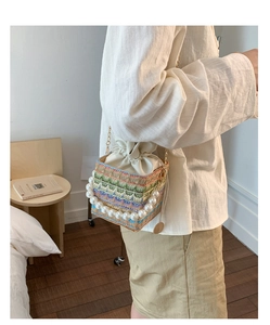 Detail of colorful woven straw bucket bag with pearl handle and drawstring lining