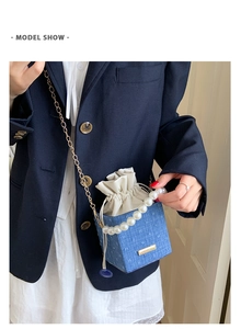 Blue textured bucket bag with pearl handle and golden chain shown on a model