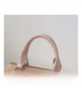 Detail of pink Boston bag showing litchi grain texture, bear print, and golden hardware