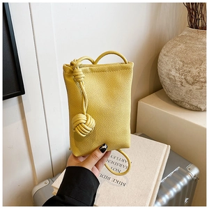 Detail of yellow lychee texture leather mini phone bag with stylish knotted shoulder strap