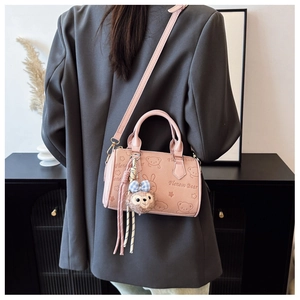 Detail of pink embossed handbag featuring cute cartoon patterns and a plush bear charm