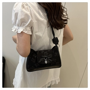 Detailansicht der schwarzen Tasche mit Blumenmuster, Seidenschleife und Herzanhänger