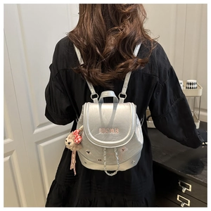 Detail of silver mini backpack featuring pink BCMB embroidery and a monkey charm