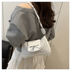 Nahaufnahme der weißen Spitzen-Tasche mit Herzanhänger und geflochtenem Riemen