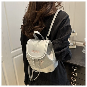 Détail d'un mini sac à dos argenté avec broderie IBCMB et bandoulière à chaîne au dos