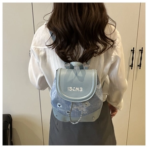 Détail d'un sac à dos en denim bleu clair avec broderie IBCMB et écussons de dessin animé