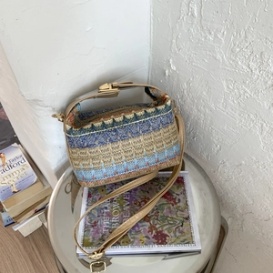 Ethnic straw tote bag with blue wavy patterns and adjustable leather strap