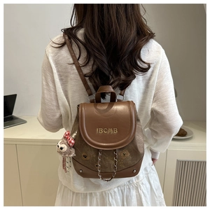 Detail of vintage brown backpack with IBCMB embroidery and cute bear plush charm