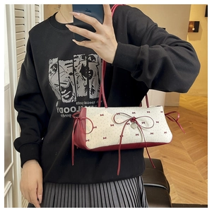 Détail du pendentif cœur et du nœud rouge sur un sac baguette à fleurs