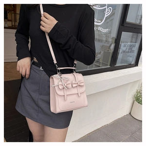 Close-up of pink faux leather bag featuring double bow accents and a pearl charm