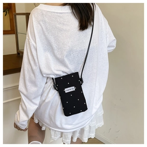 Detail of black floral canvas crossbody bag featuring Creative Cat label and slim strap