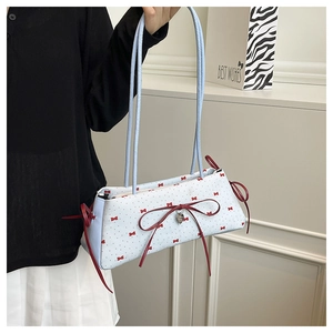 Détail du sac d'épaule en tissu bleu clair avec nœuds rouges et breloque cœur argentée