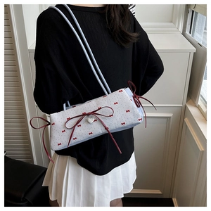 Détail du sac à bandoulière bleu clair avec nœuds rouges et pendentif cœur argenté