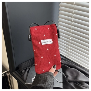 Close-up of red chiffon crossbody phone bag with white floral pattern and a creative label