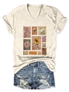 Flat lay of cream V-neck T-shirt with vintage floral stamps and ripped denim shorts