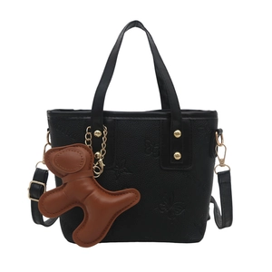 Bolso cubo negro con grabado de mariposa y colgante de oso marrón sobre fondo blanco