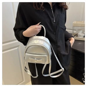 Silver metallic mini backpack with bow detail shown on black shirt for contrast