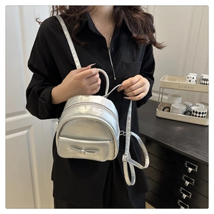 Detailed view of silver mini backpack with ribbon bow and smooth metallic texture