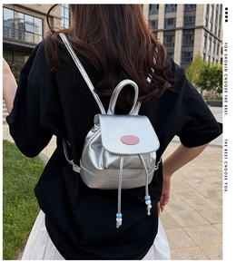 Silver mini backpack with drawstring and blue bead charms worn by model in city