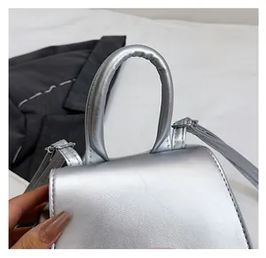Detail of silver metallic handbag showing smooth pearl texture and durable round handle