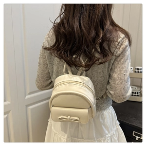 Mini cream PU leather shell backpack with bow detail worn on model back