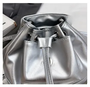 Detail of the silver metallic bucket bag showing the drawstring closure and metal eyelets